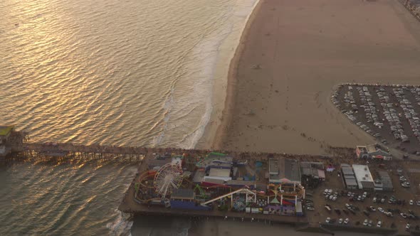 AERIAL Flying Away From Santa Monica Pier Los Angeles at Beautiful Sunset with Tourists Pedestrians alt