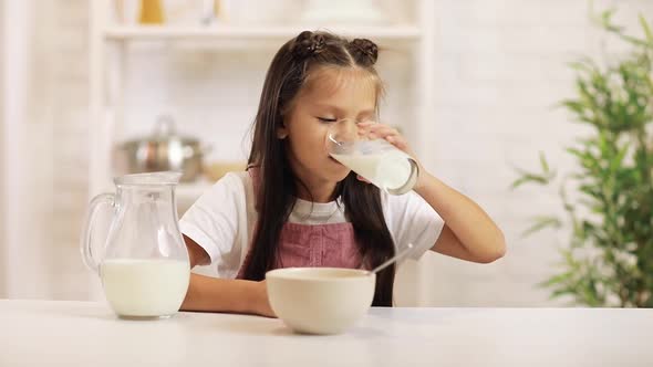 Little Child Girl Drinking Milk in the Kitchen.