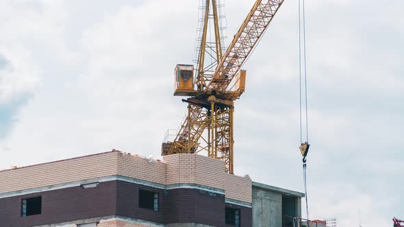 Timelapse footage of a high crane works on building site with a house alt