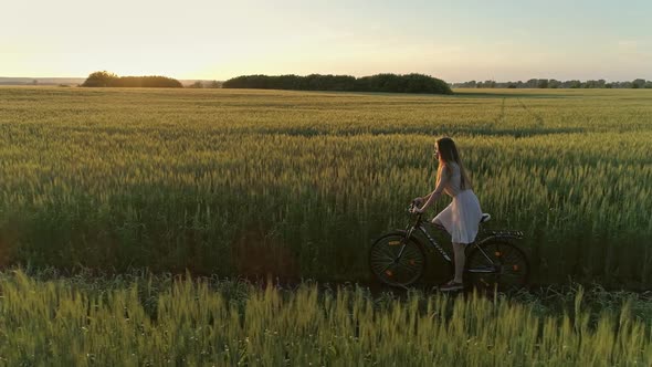 Girl on Bicycle in Green Field Drone Shooting alt