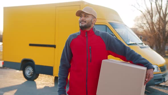 Delivery Boy Carrying A Cardboard Box A Yellow Truck Behind Him  Parcel Delivery alt