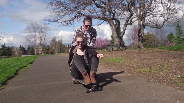 Two young people at park playing on skateboard
