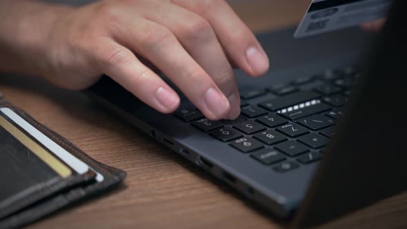 male hands are typing credit card details for online payment.