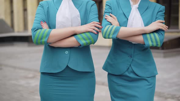 Two Unrecognizable Slim Young Women in Blue Stewardess Uniform Crossing Hands. Confident Elegant alt