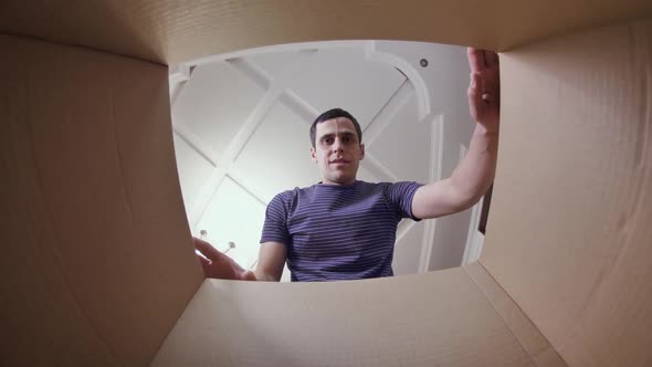 Unhappy Man Opening Cardboard Box alt