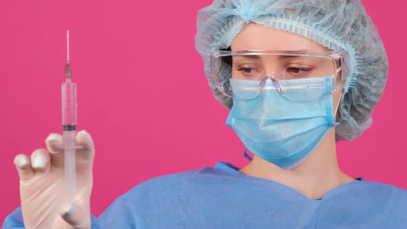 Professional Female Doctor Holds a Syringe with a Vaccine on a Pink Background alt