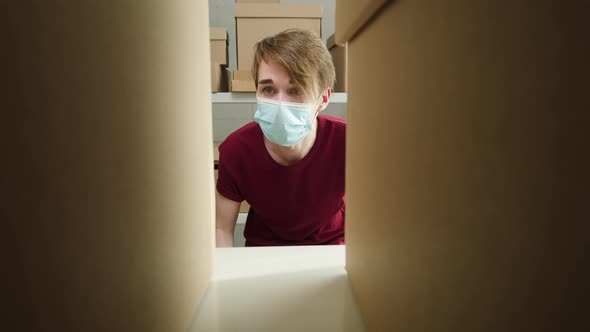 Man Wearing Medical Face Mask and Protective Gloves Putting Parcel on Shelf Employee of Warehouse alt