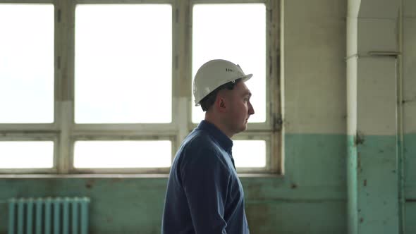 Inspector in Helmet Walks Along the Corridor of an Old Building Looks Around alt