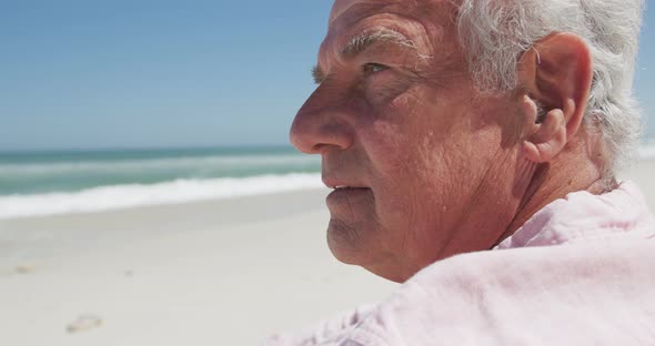 Close up view of thoughtful senior caucasian man sitting on the beach alt