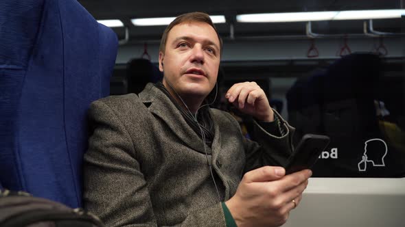 Mature Guy in Gray Coat Riding on Train Using Mobile Phone Discusses Work Processes on Videocall alt
