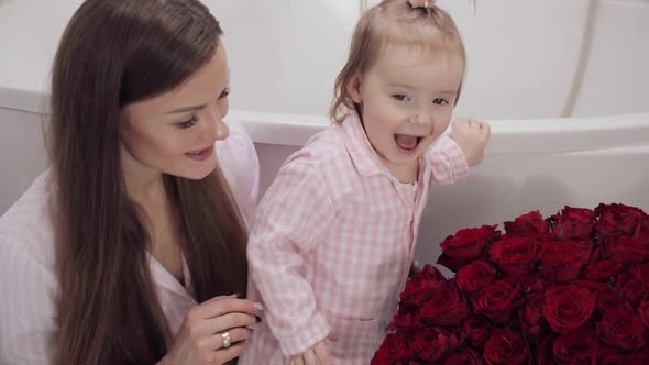 Side View of Mother and Little Daughter Smelling Flowers