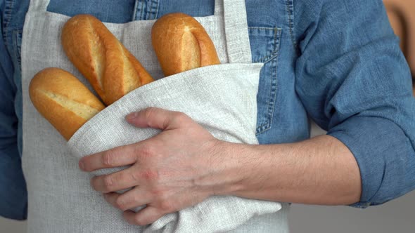 Hands Hold Freshly Baked French Baguette in Kitchen Linen Towel