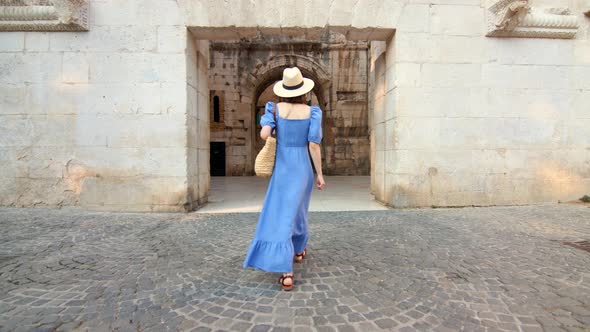 Young woman in a blue dress walking on the street in the city. Split, Croatia alt