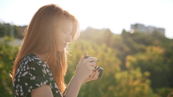 Redhead Young Girl n Black and White Dress Adjusts Film Camera Then Shoots in Slowmotion alt