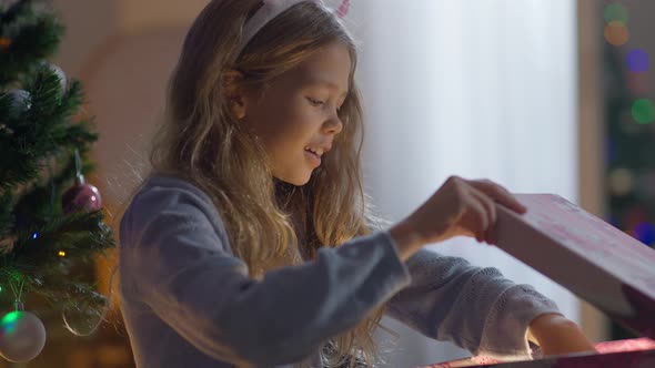 Portrait of Cheerful Excited Happy Girl Opening Gift Box with Light Inside alt