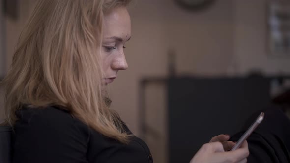 Handheld Shot of Blond Woman Sitting Texting on the Phone alt