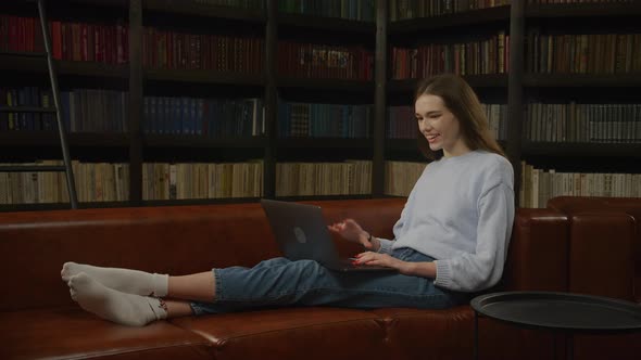 Caucasian Woman Student Waving Her Hand in a Greeting During a Video Call with Friends on Her Laptop alt