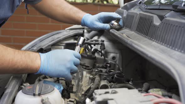 Caucasian Man in Protective Gloves Putting in and Conncecting Ignition Coils in Car Engine Bay