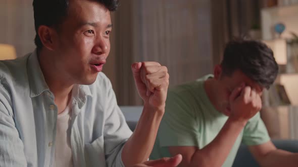 Asian Friends Playing Video Games At Home. Male Happy To Win And Another Man Feeling Disappointed alt