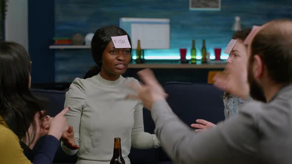 Group of Multiethnic People Laughing While Playing Guess Who Game Using Stickey Notes alt