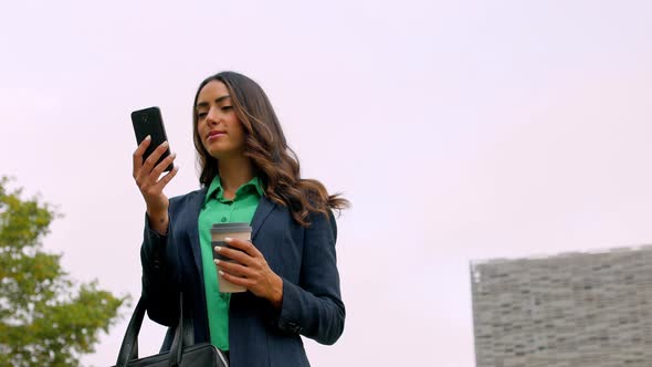Businesswoman holding reusable cup while reading text messages alt