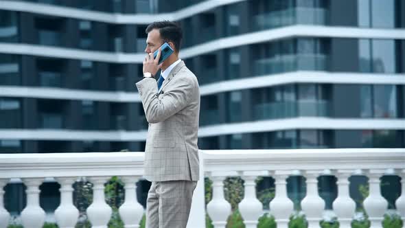 Young Businessman Walking On Street And Talking On Phone.