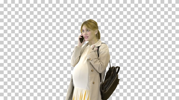 Pregnant woman in a cloak with backpack talking on the alt