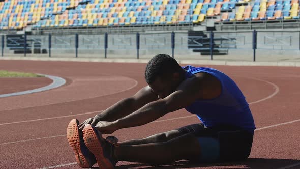 Hispanic Athlete Completing Set of Daily Exercises Sitting on Running Track alt