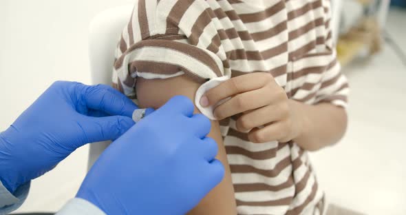 Male Pediatrician Giving a Vaccine Shot to a Black Kid alt