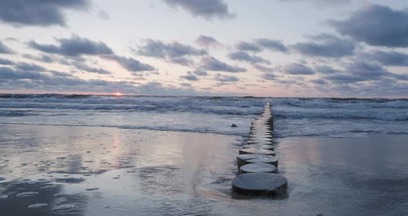 Breakwater of Larch Logs. Strengthening the Seashore To Keep the Sand on the Beach. Gorgeous Sunset alt