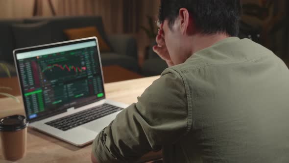Upset Asian Man Trader Investor Sitting In A Wheelchair Trading Cryptocurrency On Laptop alt
