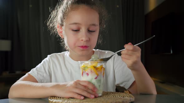Child Eats Milk Yogurt with Tropical Fruits alt