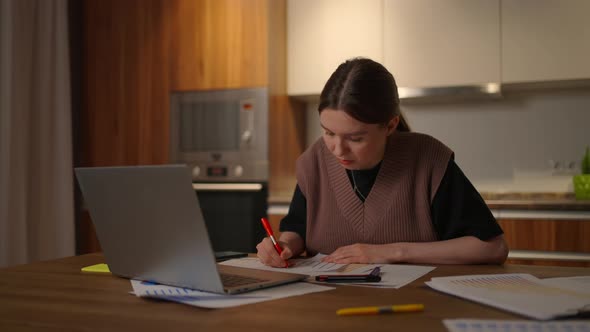 Portrait of a Woman Working Remotely in a Home Office at a Desk with a Laptop and Notes Data on a alt
