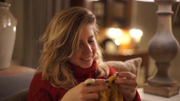 Young woman knitting at home alt