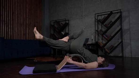 a Woman is Lying on a Sports Mat Against a Gray Wall alt