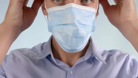 Extreme Closeup of Man Putting Disposable Face Mask Over Mouth and Nose alt
