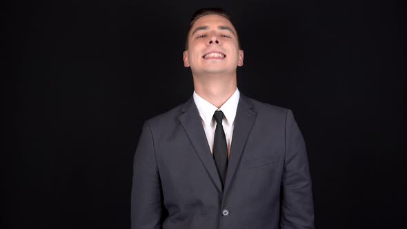 A Young Businessman Nods His Head Positively. Man in a Black Suit on a Black Background alt