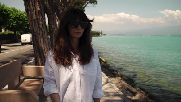 Real Time Portrait Shot of a Young Beautiful Girl Walking Along the Embankment of Lake Garda.