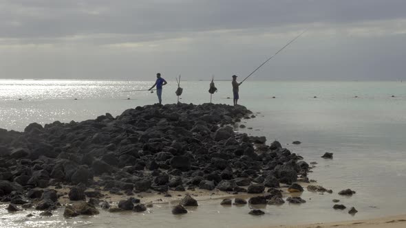 Two men fishing on the coast alt