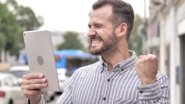 Man Cheering for Success on Tablet Outdoor alt