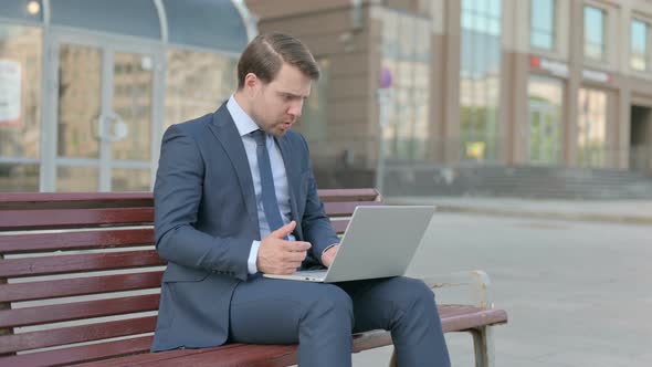Businessman Reacting to Loss on Laptop while Sitting Outdoor on Bench alt