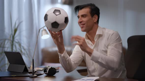 Joyful Young Middle Eastern Man Spinning Ball Smiling Sitting at Table in Home Office alt