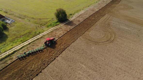 A Farmer on a Tractor Uses a Harrow Seeder, Cultivates the Soil, Prepares the Fields for Sowing alt