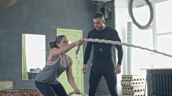 Personal Coach Teaching Woman Doing Battle Rope Exercise alt
