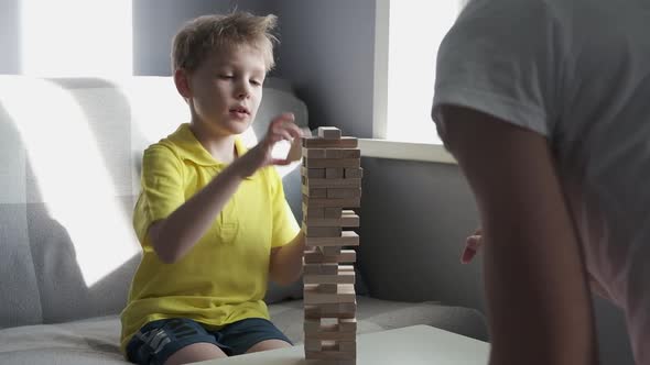 Father and Son is Playing in Board Game with Wooden Tower Together at Home