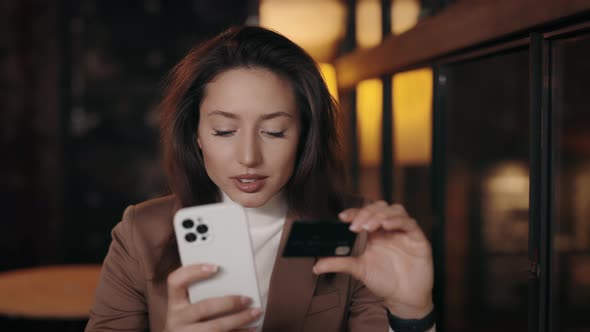Woman Sitting at Cafe and Using Smartphone with Credit Card alt
