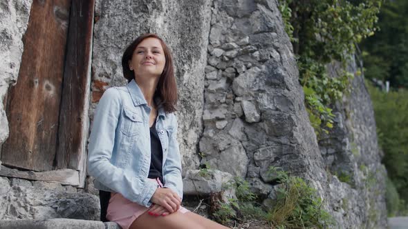 Woman Smiles While Sitting on Stone Steps alt