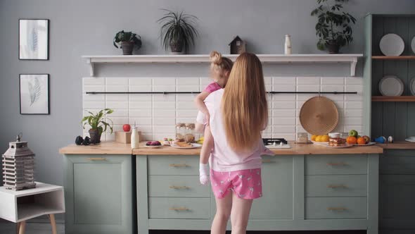 Beautiful Mother Cooking Dinner on Kitchen with Little Kid