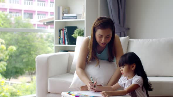 Young mother teaching cute daughter drawing on paper alt