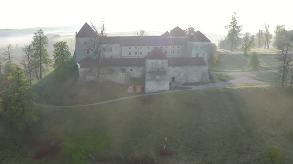 Aerial View of Svirzh Castle Near Lviv, Ukraine at Dawn. Lake, Morning Fog and Surrounding Landscape alt